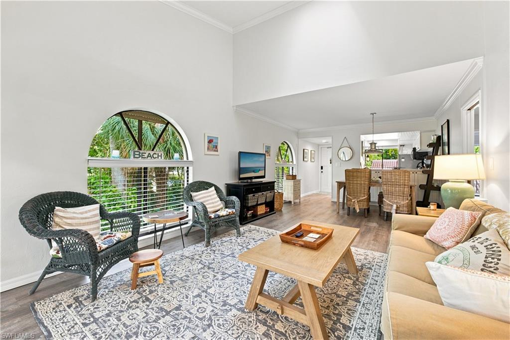 Vaulted ceiling, arched window, wood-finish flooring, crown molding, and recessed lighting