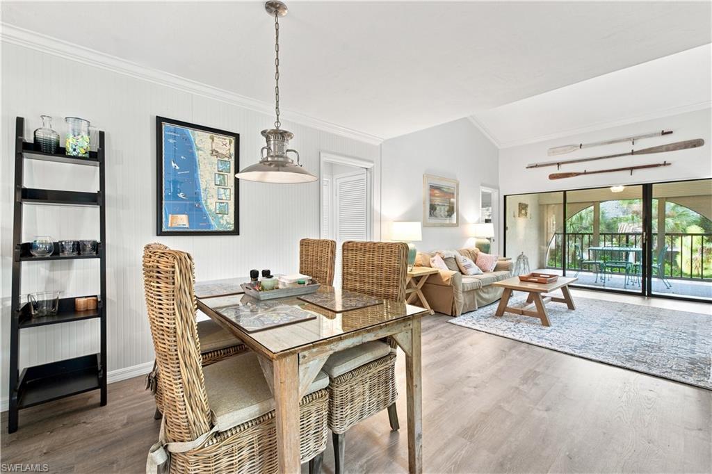 Vaulted ceiling, sliding glass doors, light wood-finish flooring, and a dining area with a pendant light fixture