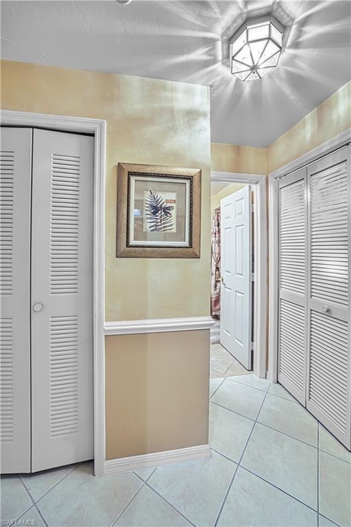 Tiled flooring with geometric patterns, interior doors with louvered panels, decorative wall trim, and a ceiling-mounted light fixture