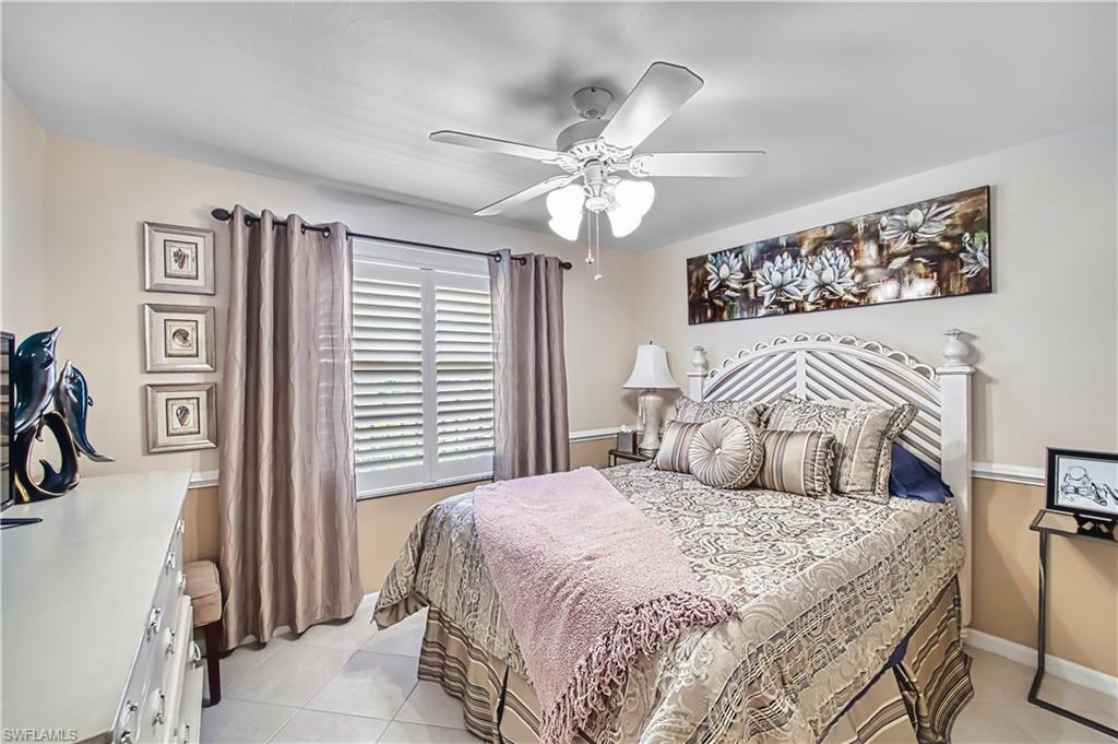 Ceiling fan with integrated lighting, window with white plantation shutters, tile flooring, and wall molding