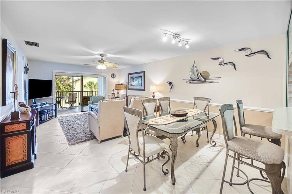 Expansive tiled flooring throughout, glass-top dining table, track lighting, ceiling fan, and a balcony with railings