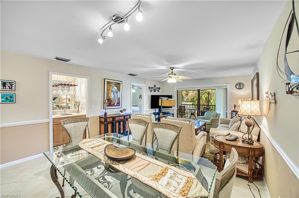 Open-concept living space featuring tile flooring, a built-in wet bar with cabinetry, ceiling fan, and sliding glass doors leading to an outdoor area