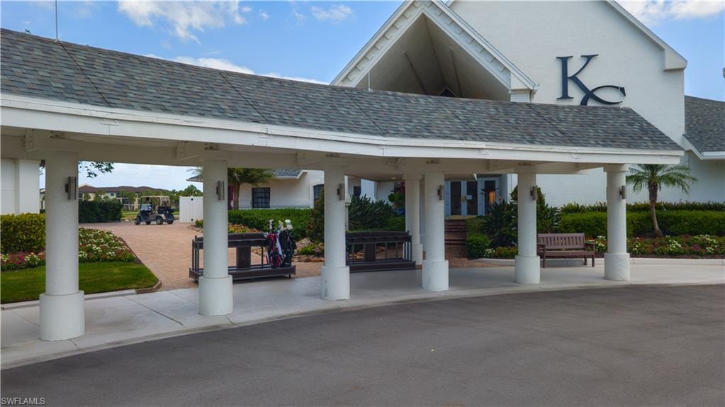 Covered entryway featuring multiple support columns, a shingled roof, and exterior wall sconces