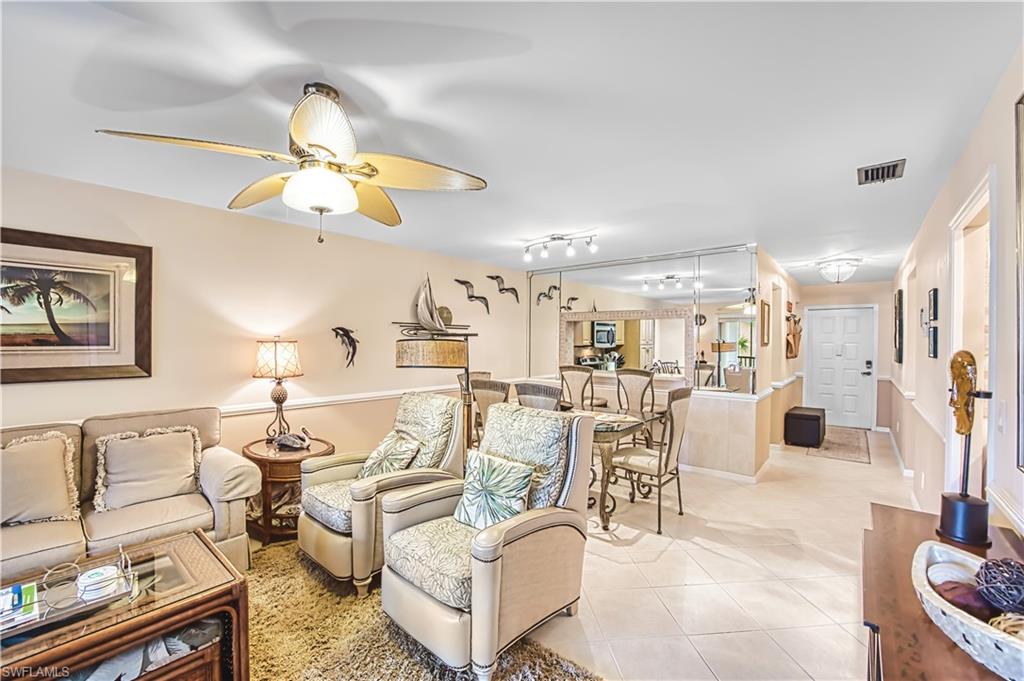 Ceiling fan with integrated lighting, wall-mounted mirror panels, recessed lighting, tile flooring, and a paneled entry door
