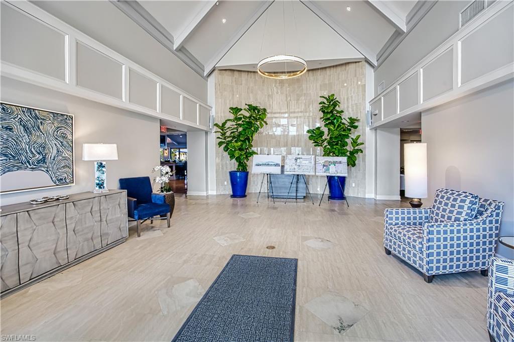 Vaulted ceiling, recessed lighting, tile flooring, accent wall paneling, and a circular chandelier