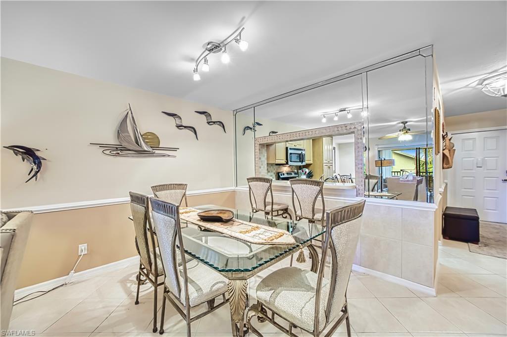 Dining area featuring mirrored walls, a track lighting fixture, and tiled flooring