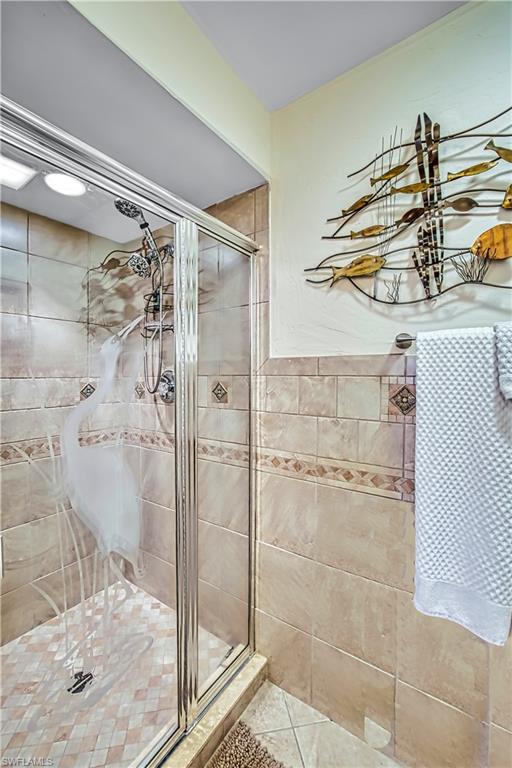 Tiled shower enclosure with a glass sliding door, integrated shower head, and patterned tile accents