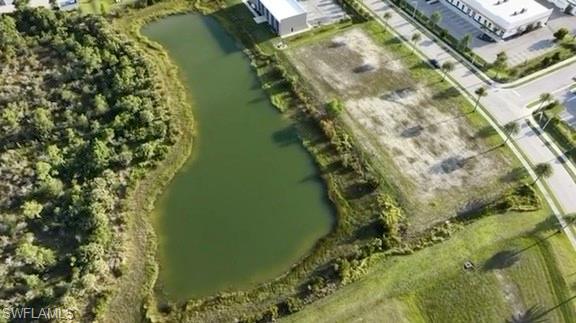 Expansive lot featuring a water body, bordered by mature trees and paved roads