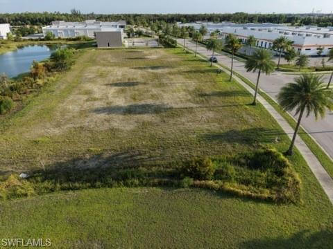 Expansive land parcel with surrounding commercial structures, a paved street, and mature palm trees