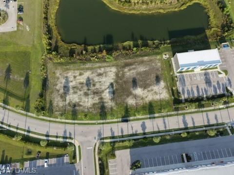 Expansive lot featuring a water body, paved roadways, and landscaped green areas