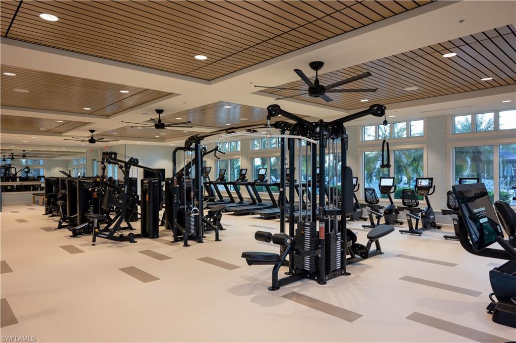 Fitness center with extensive exercise equipment, wood-finish ceiling panels, recessed lighting, and large windows