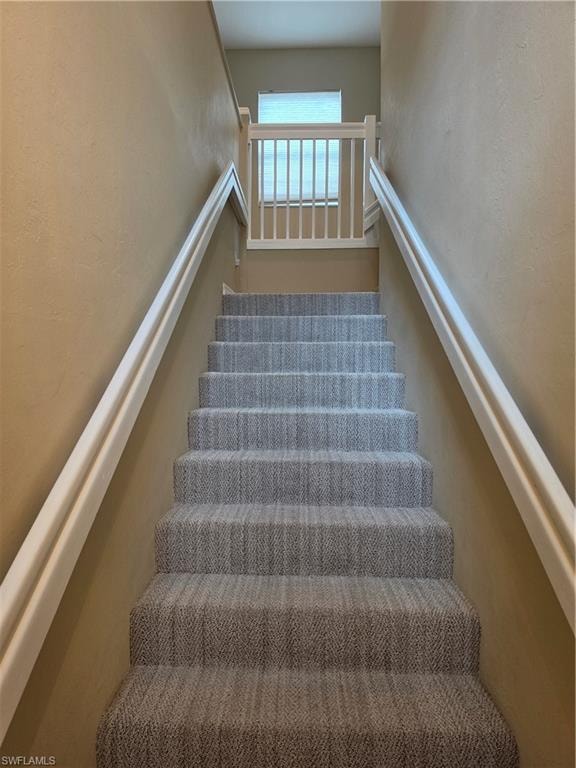 Carpeted staircase with white handrails and a built-in gate