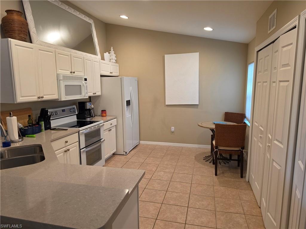 Kitchen featuring light-toned cabinetry, stainless steel appliances, stone-look countertops, and tile flooring