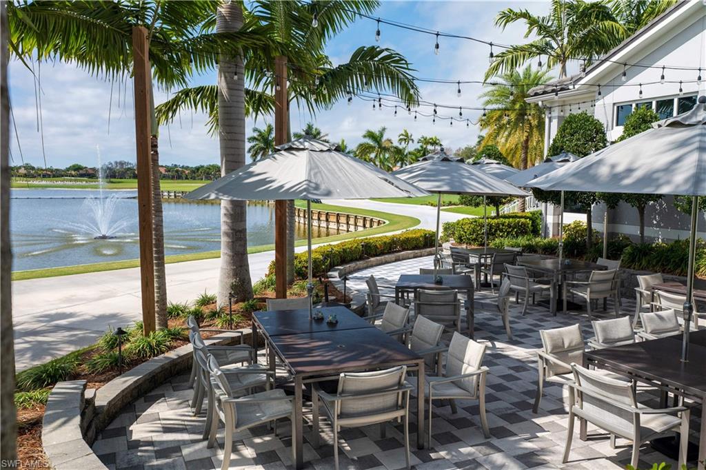 Paver patio with multiple outdoor dining areas, surrounded by manicured landscaping and mature palm trees