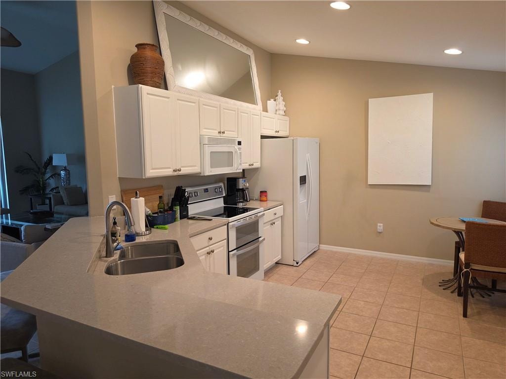 Kitchen featuring white cabinetry, light-toned countertops, a stainless steel double basin sink, recessed lighting, and tile flooring