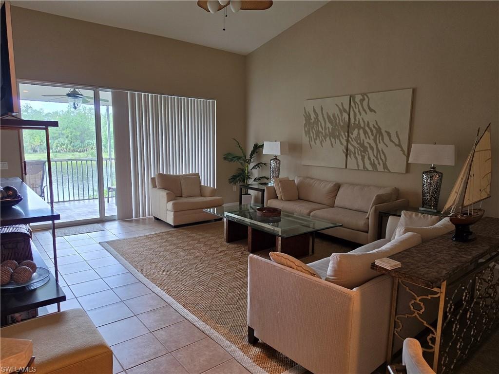 Vaulted ceiling, tiled flooring, glass sliding doors, outdoor balcony, and water feature