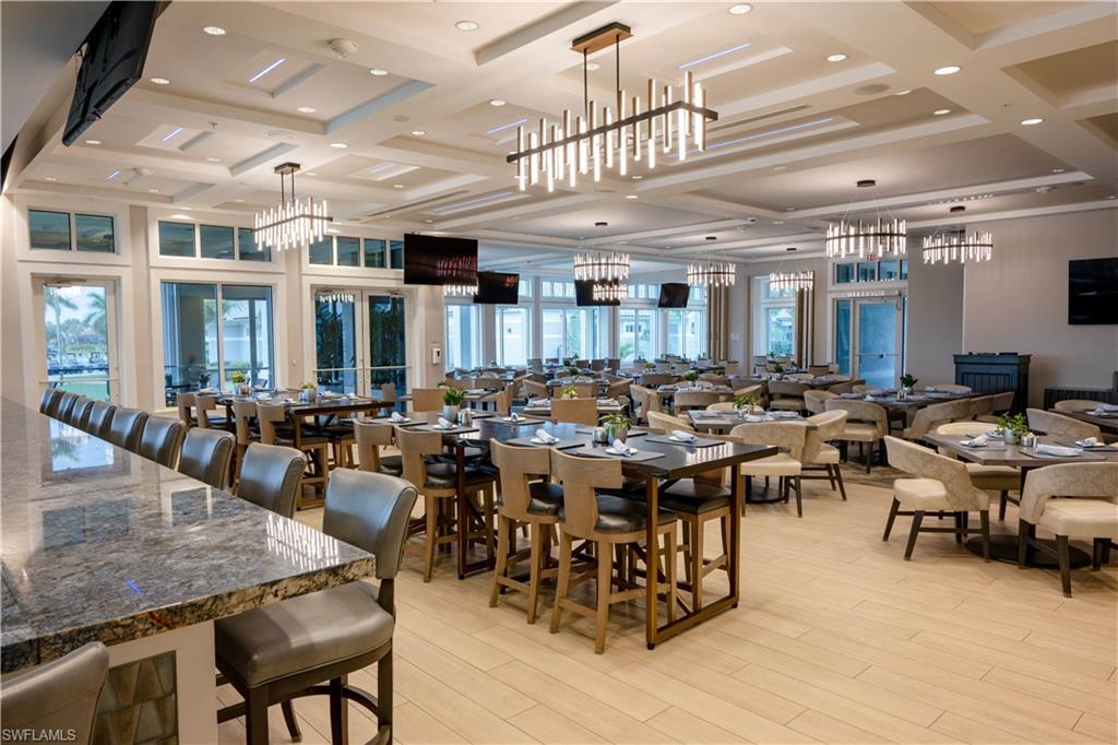 Spacious interior with multiple dining areas, light wood-finish flooring, and tray ceilings