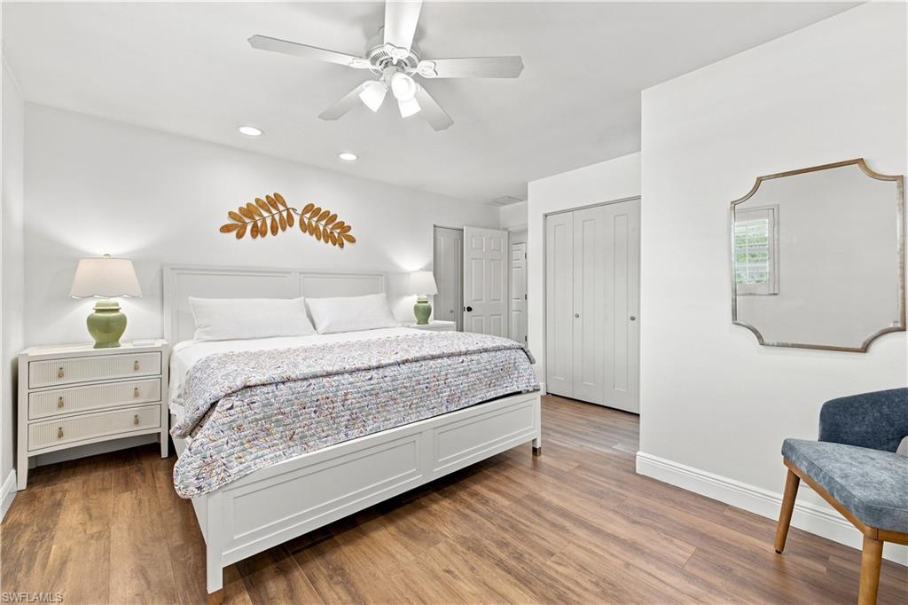 Wood-finish flooring with white baseboards, recessed ceiling lights, and a ceiling fan with integrated lighting