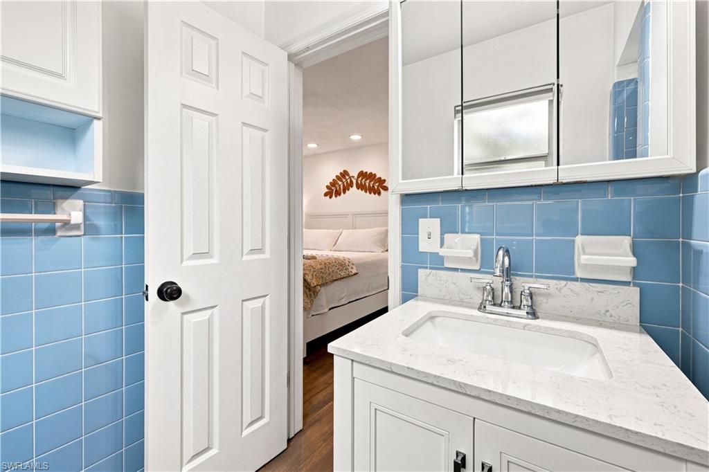 White vanity with a quartz countertop and integrated sink, complemented by a chrome faucet