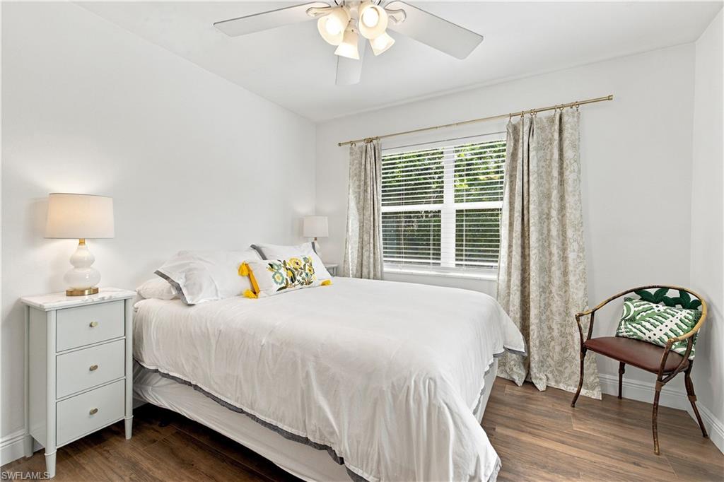 Wood-finish flooring, white walls, ceiling fan, and window with blinds