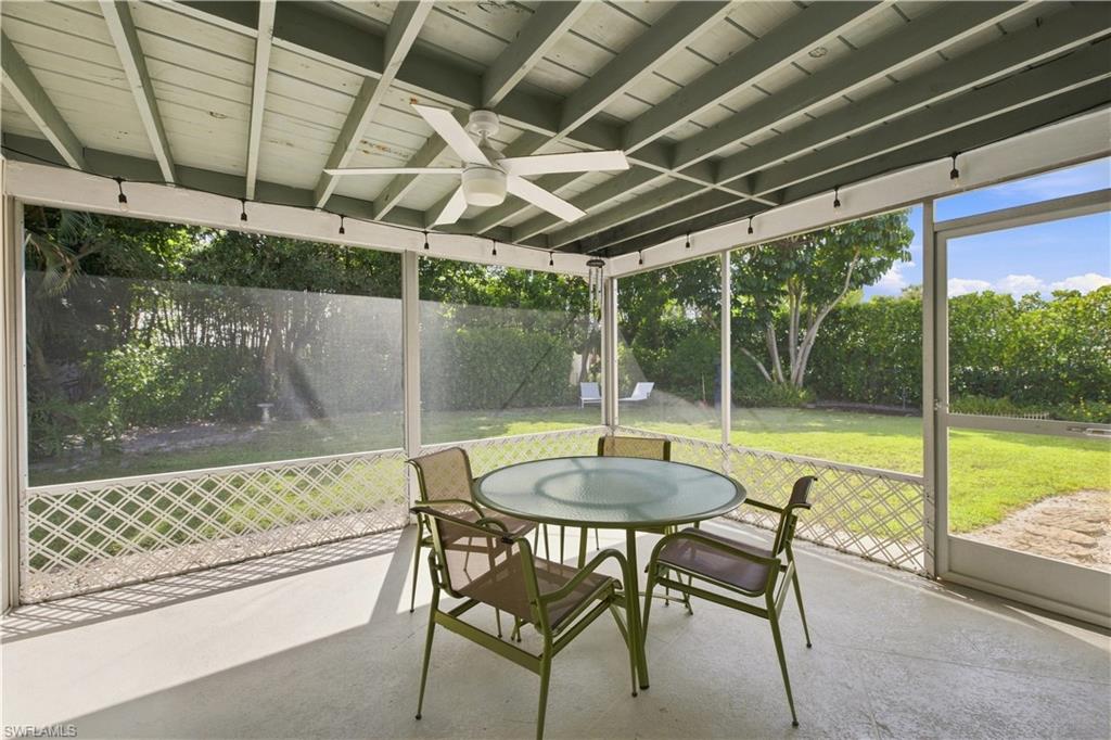 Screened patio with a ceiling fan, exposed wood beam ceiling, concrete flooring, and a landscaped backyard