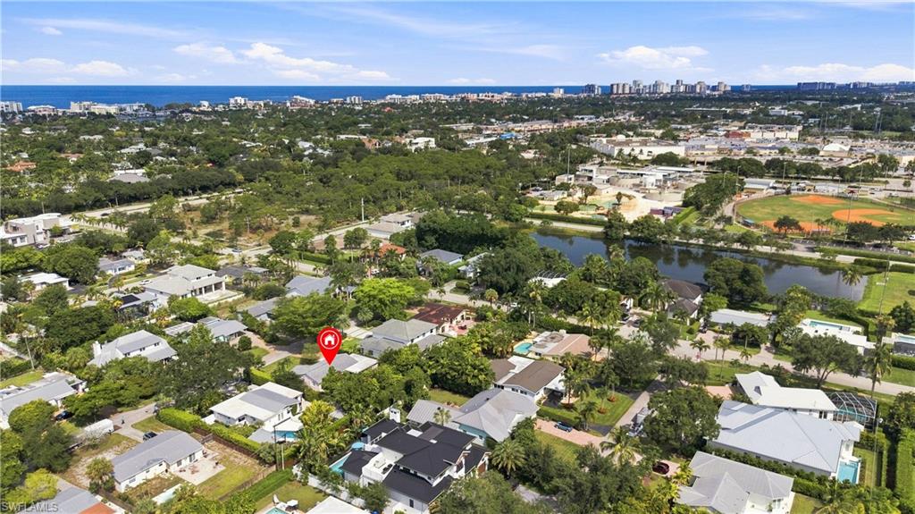 Residential neighborhood setting with mature trees, a nearby canal, and distant coastal line