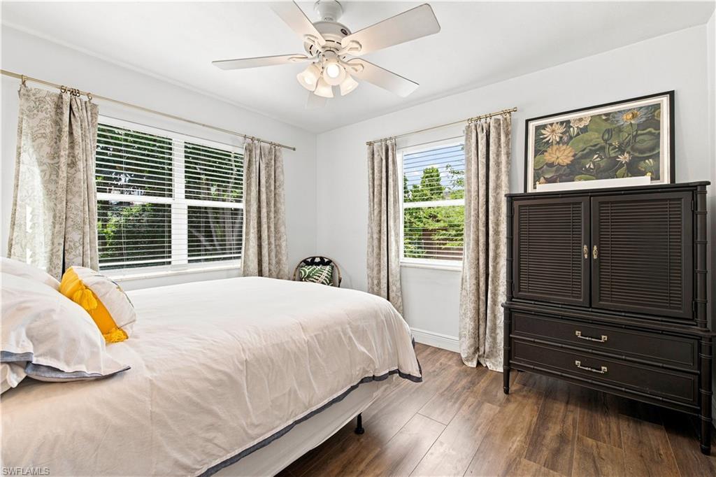 Wood-finish flooring, white ceiling fan with integrated lighting, window blinds, and white walls