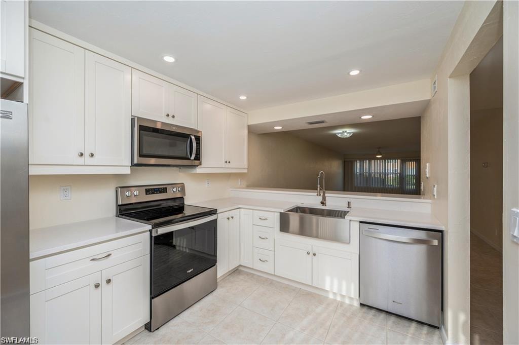 Kitchen featuring appliances with stainless steel finishes, light countertops, white cabinetry, recessed lighting, and light tile patterned flooring