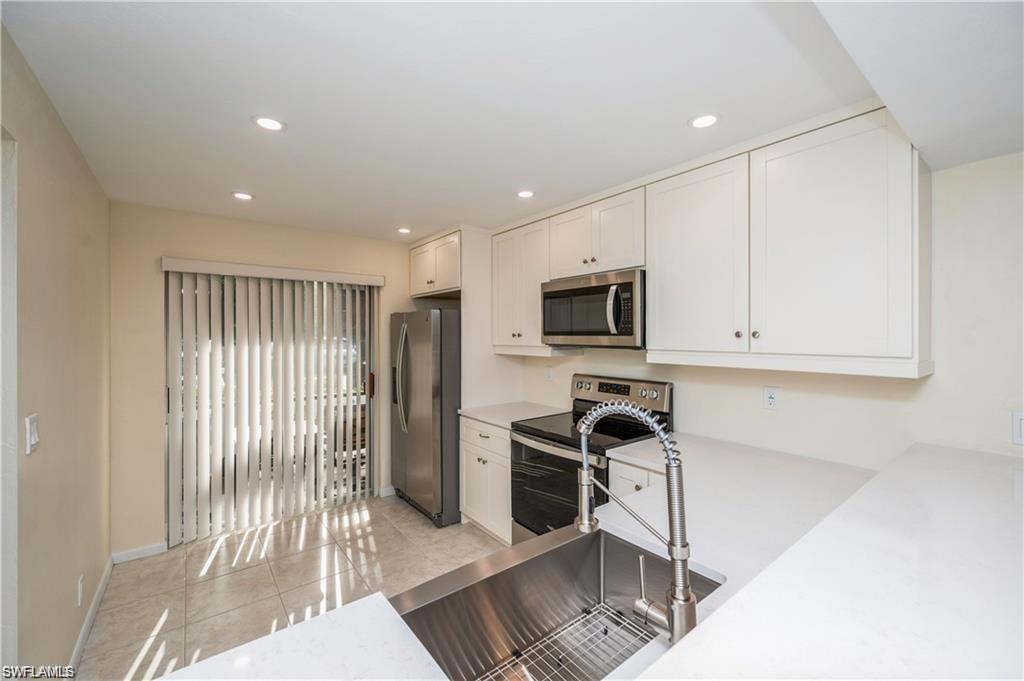 Kitchen featuring stainless steel appliances, white cabinets, light countertops, light tile patterned floors, and recessed lighting