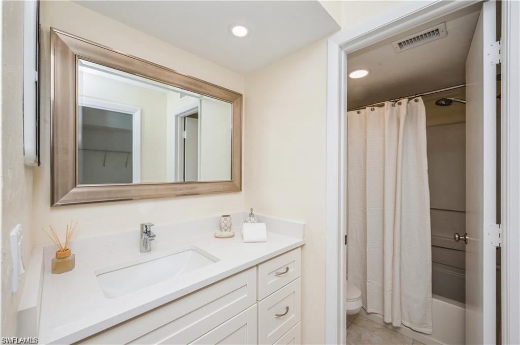 Bathroom featuring vanity, shower / bath combo with shower curtain, and recessed lighting