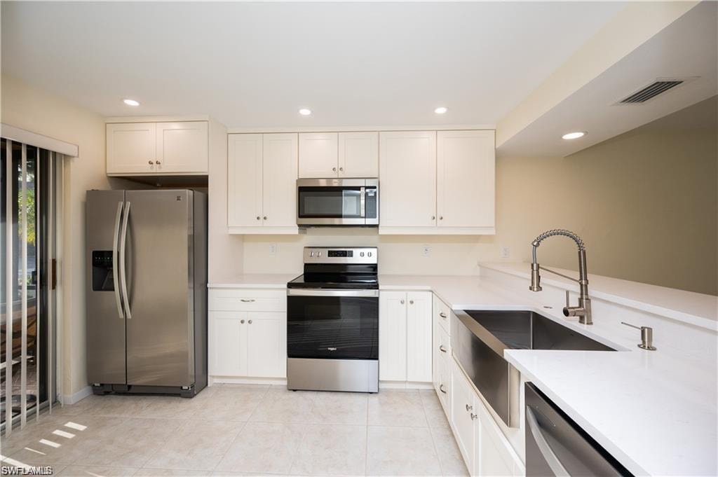 Kitchen featuring stainless steel appliances, light countertops, white cabinets, recessed lighting, and light tile patterned floors