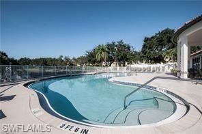 Freeform swimming pool featuring integrated steps, handrail, and surrounding concrete decking