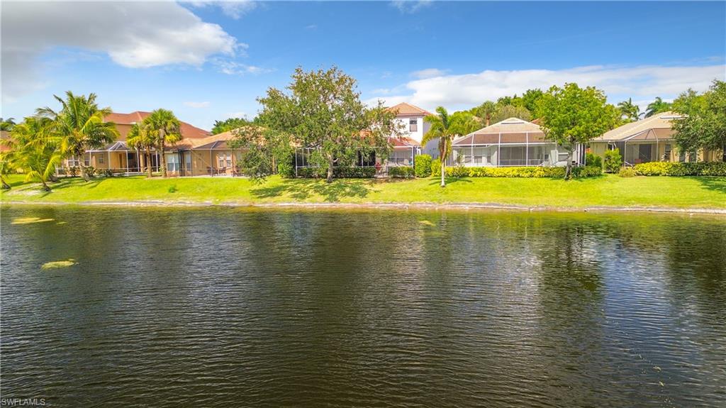 Waterfront property with expansive green lawn, mature landscaping, and screened outdoor living areas
