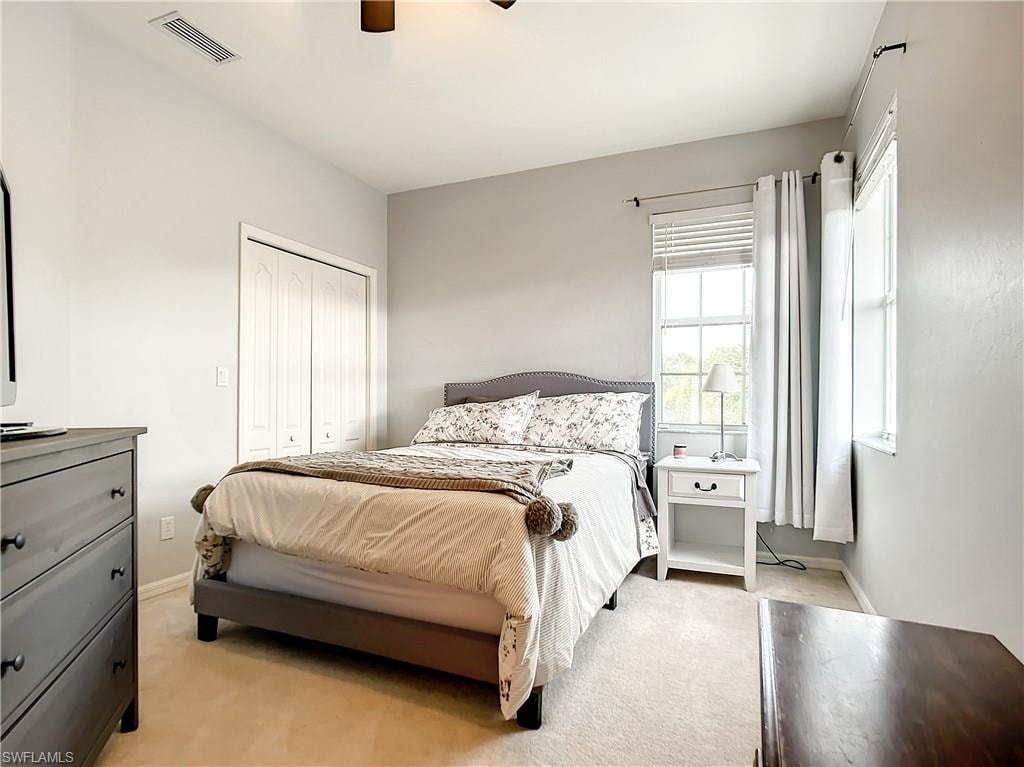 Neutral color palette, two windows with blinds, bi-fold closet doors, ceiling fan, and carpeted flooring