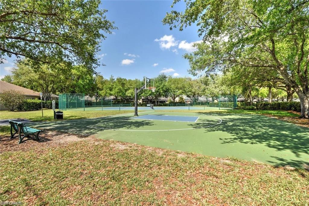 Recreational court with basketball hoop and tennis courts, surrounded by mature trees