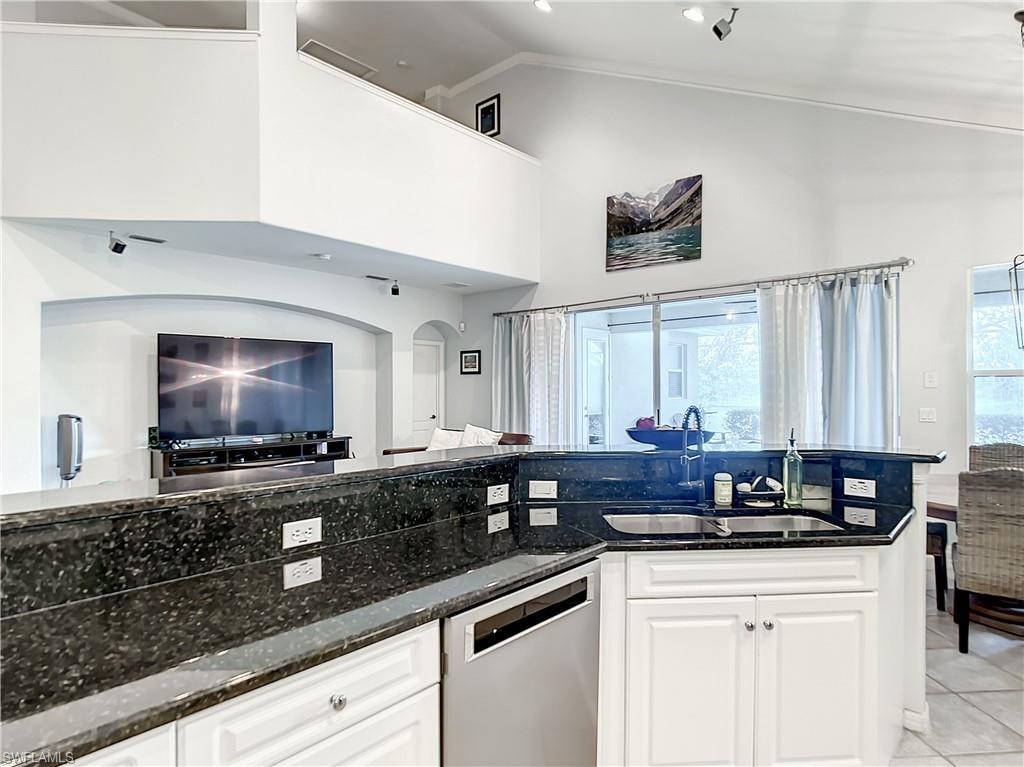 Kitchen featuring dark stone countertops, white cabinetry with silver hardware, and a stainless steel dishwasher