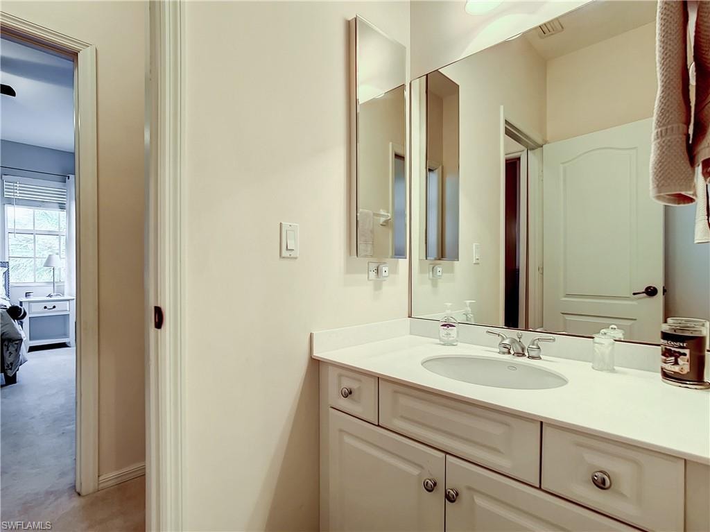 Vanity with integrated sink, chrome faucet, wall-mounted mirror, and cabinet storage
