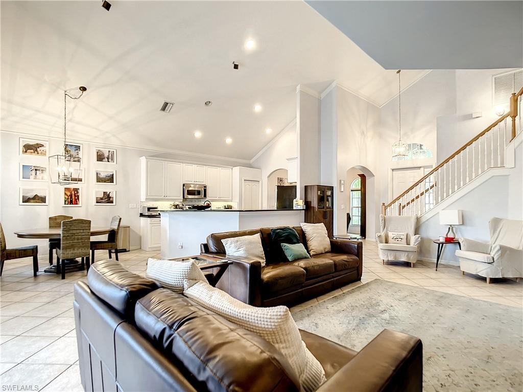Vaulted ceilings with recessed lighting, tile flooring, and a kitchen featuring white cabinetry and stainless steel appliances