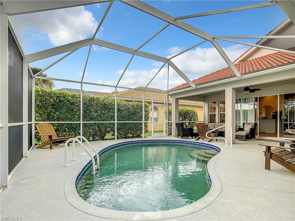 Screened-in outdoor living space featuring a freeform pool, integrated spa, and expansive patio