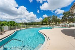 Resort-style pool with integrated steps, surrounded by a paved deck and a perimeter fence