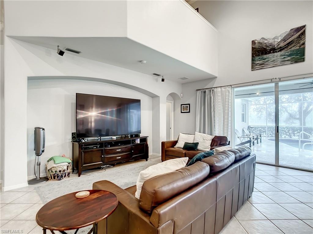 Vaulted ceiling, arched entryway, sliding glass doors, tile flooring, and a screened outdoor area with a pool