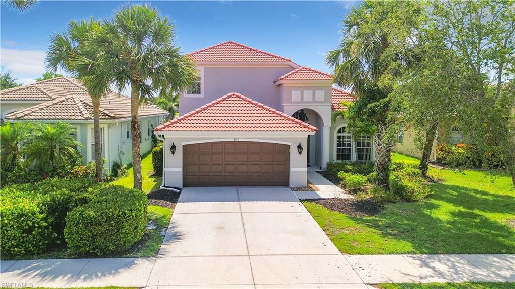 Two-story stucco exterior with a tile roof, an integrated two-car garage, and a concrete driveway