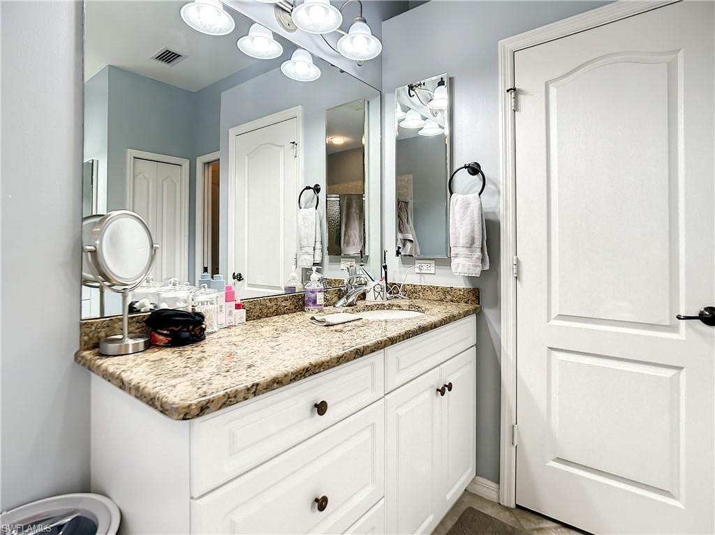 Vanity with granite countertop, integrated sink, and white cabinetry