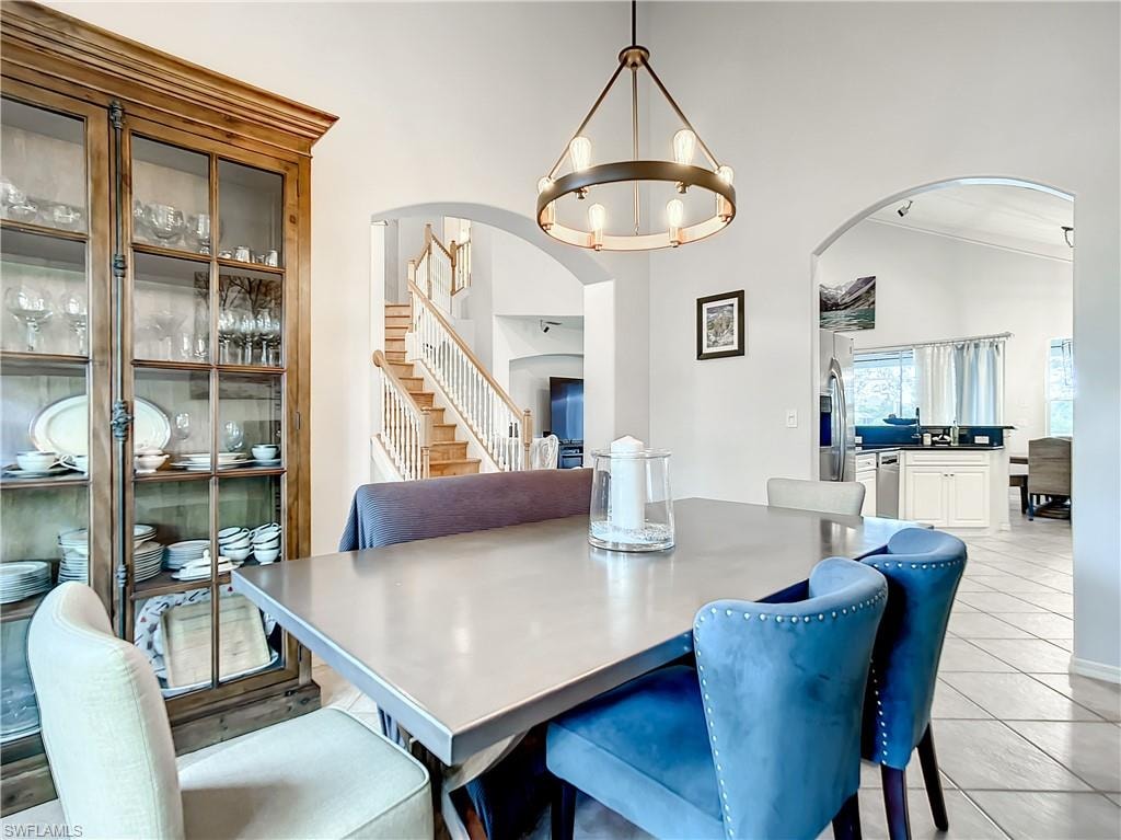 Spacious dining area featuring an arched doorway, wood staircase, and a built-in display cabinet