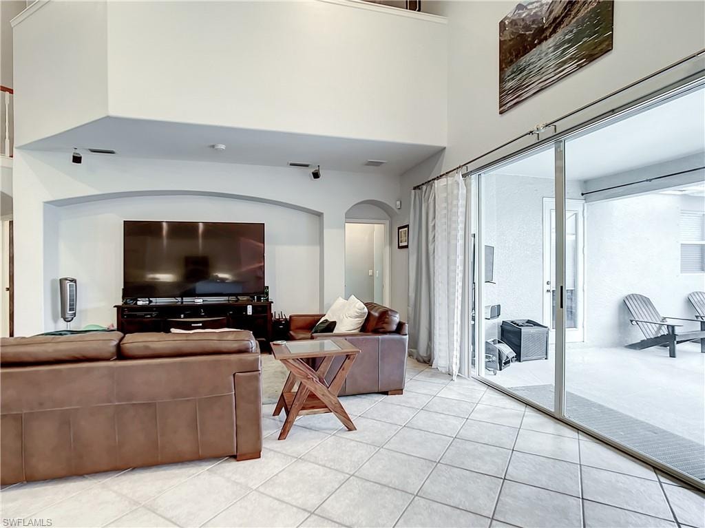 Two-story living area with high ceilings, featuring a recessed arched wall and large format tile flooring