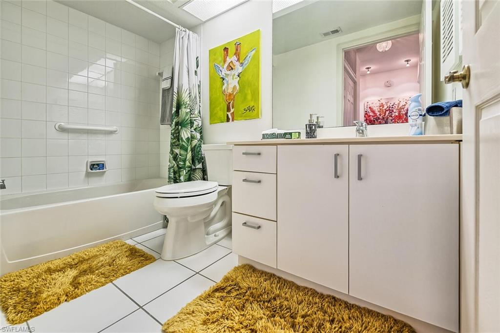 Full bathroom with tile patterned floors, shower / bath combo, vanity, and toilet