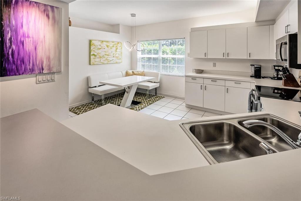 Kitchen featuring range, sink, white cabinets, hanging light fixtures, and light tile patterned floors