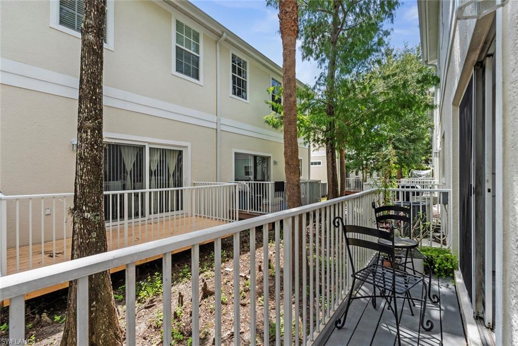 Outdoor deck with white railings, a sliding glass door entry, and mature trees providing natural screening