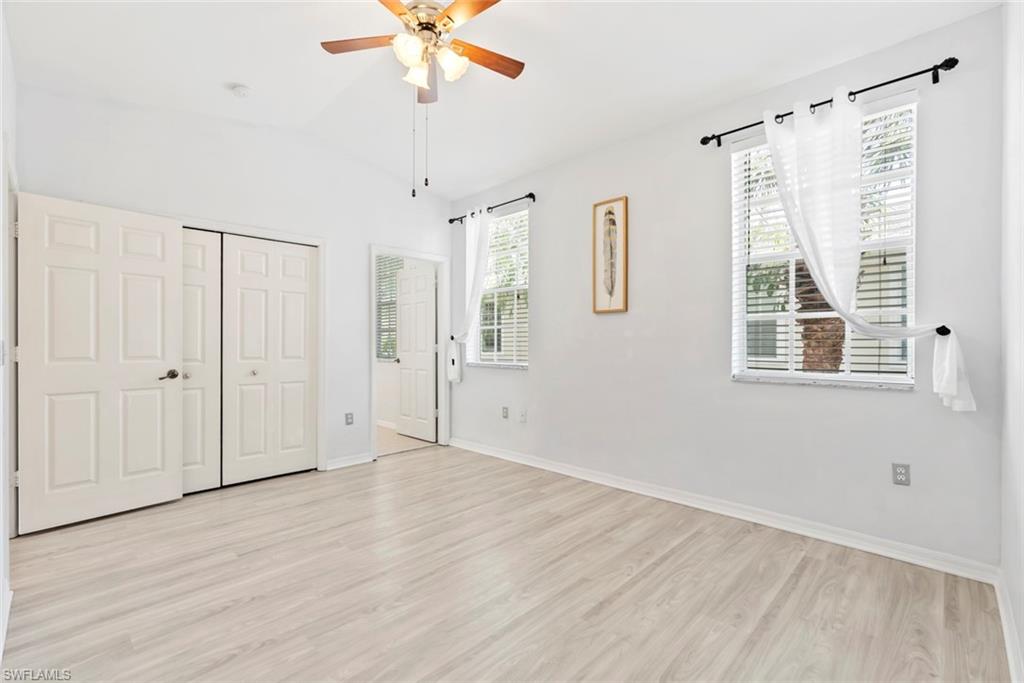Vaulted ceiling, wood-finish flooring, two windows with blinds, bi-fold closet doors, and an overhead ceiling fan