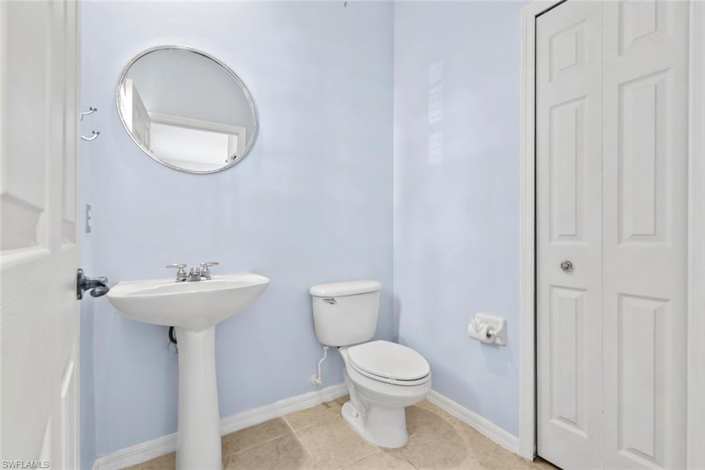 Pedestal sink with chrome faucet, oval wall mirror, and bi-fold closet door